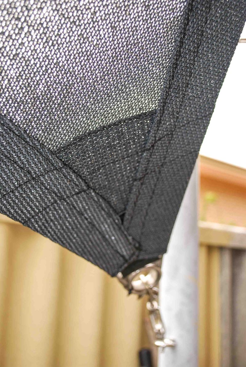 Black shade sail corner with reinforced webbing attached to a galvanised steel post