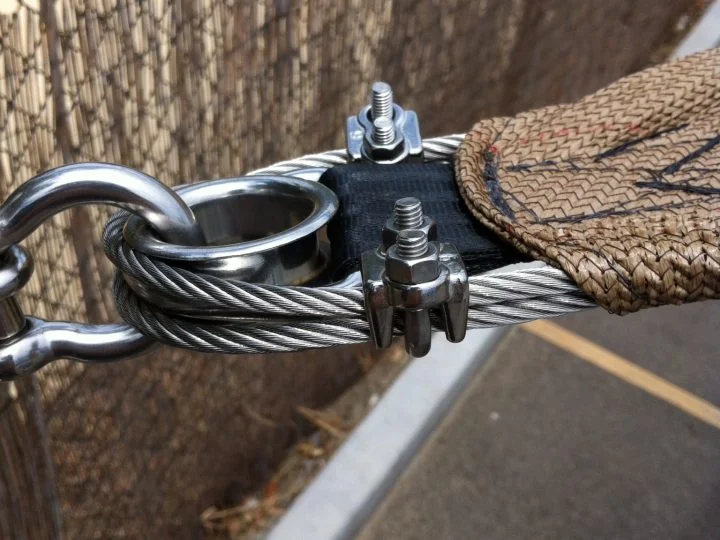 Perimeter wire rope with a stainless thimble, shackle and wire rope grips at a sail corner