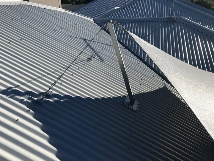 Galvanised steel shade sail post bolted to a base plate on a metal roof with stay wires