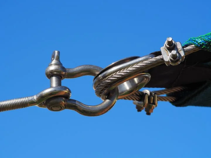 Stainless steel dee shackle, turnbuckle and wire rope at the corner of a shade sail
