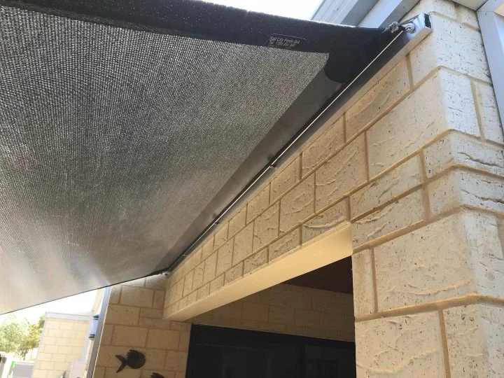 Shade sail edge fixed into a continuous wall track along a limestone wall